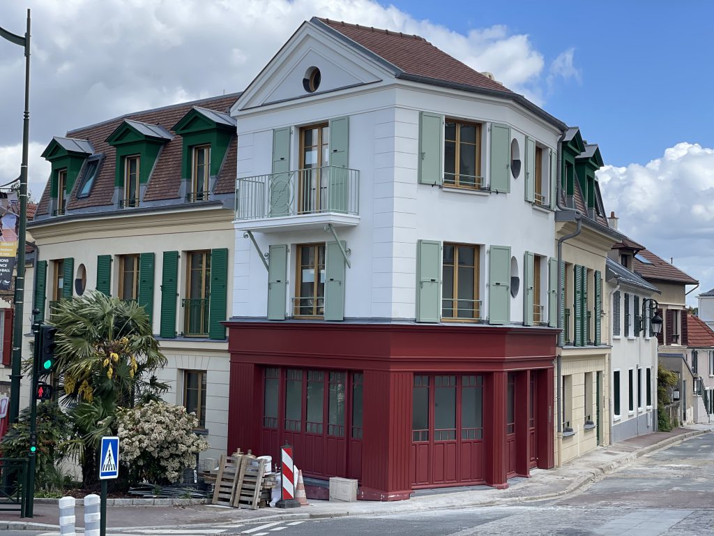 Vue globale de la façade de la résidence du 14-16 Mairie composée d'un magasin rouge en rez-de-chaussée et de logements au dessus